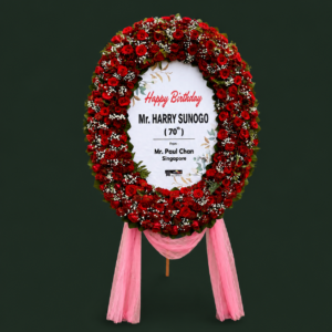 Bunga standing surabaya bentuk oval ucapan Happy 70th Birthday Mr Harry Sunogo dari Mr Paul Chan Singapore dengan lingkaran penuh mawar merah